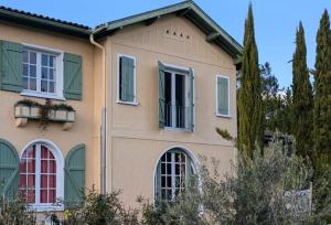 una casa con ventanas verdes en L Entre Deux chambres d hôtes, en Belin-Beliet