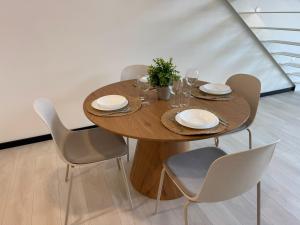 a wooden table with chairs and plates and wine glasses at Apartamentos El Puerto Ayamonte in Ayamonte
