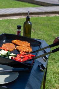 a grill with hamburgers and vegetables on a table at La Villa face au Lac in Saramon