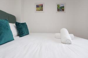 a white bed with a stuffed animal sitting on it at Kites House Long Stays Sleep 8 Free Parking and WI-FI in Bristol