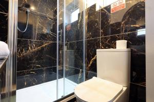 a bathroom with a toilet and a glass shower at Kites House Long Stays Sleep 8 Free Parking and WI-FI in Bristol +5 photos