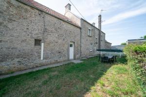 an external view of a brick building with a table and chairs at La Brise de Mer - 10min de la Plage in Les Moitiers-dʼAllonne