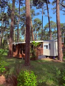 a small white house in the middle of trees at Mobil-home plage des casernes in Seignosse