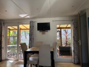 a dining room with a table and a television on the wall at Mobil-home plage des casernes in Seignosse