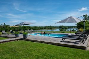 a pool with chairs and umbrellas in a yard at La Villa face au Lac in Saramon +27 photos