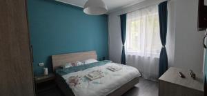 ブラショヴにあるLUNA APARTMENTの青い壁と窓のあるベッドのある寝室