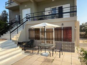 a table and chairs with an umbrella in front of a house at Marys Home Eretria in Malakóndas