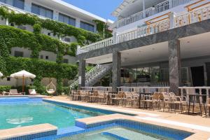 a hotel swimming pool with tables and chairs next to a building at Olympic Kosmas Hotel- Hanioti in Hanioti