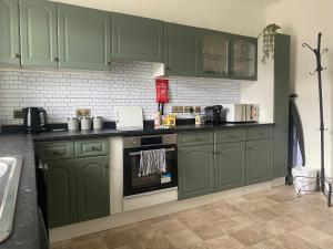 a kitchen with green cabinets and a stove at The Flat in central Kirkby Stephen in Kirkby Stephen