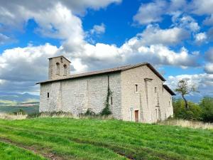 an old church on a hill with green grass at Da MammaMimma in Cascia