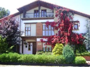 Una casa con flores rojas al costado. en Apartamentos Dos Robles, en Somo