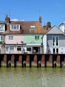 a dock in front of a house next to water at Dove Cottage is a Central, Riverside, Charming Victorian Cottage in Arundel