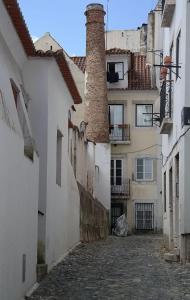 an alley with a building with a brick chimney at Alfama with a view in Lisbon