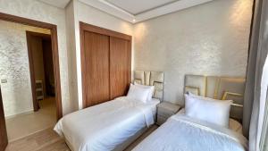 deux lits dans une chambre avec des draps blancs dans l'établissement N8 appartement, 3 Chambres Haut de Gamme, a Deux Pas de l Ocean et du Mall, à Rabat