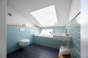 a bathroom with a toilet and a sink and a skylight at Elsas Enkel - Ferienwohnung Gesa in Waabs