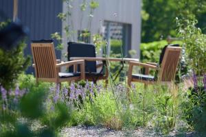 three chairs and a table in a garden with purple flowers at Elsas Enkel - Ferienwohnung Meta in Waabs