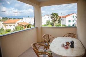 a table and chairs on a balcony with a window at Apartments Mirakul in Lopar