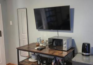 a microwave on a table with a television on a wall at Amper Daar in Beaufort West
