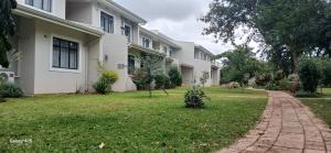 Casa blanca con entrada de ladrillo en Khaya Apartments Victoria Falls Estate, en Victoria Falls