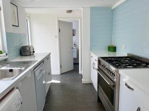a kitchen with a stove and a sink at Stylish Victorian Cottage, 2mins from Whitstable Harbour & Shops in Whitstable