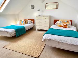 a bedroom with two beds and a dresser at Stylish Victorian Cottage, 2mins from Whitstable Harbour & Shops in Whitstable