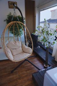 a hanging chair in a room with flowers and a window at Teatro Massimo Terrace relax suite in Palermo