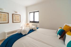 a bedroom with a large white bed with towels on it at Cascais Bay in Cascais