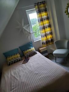 a bedroom with a bed and a chair and a window at Artist's house for rent in Guérande