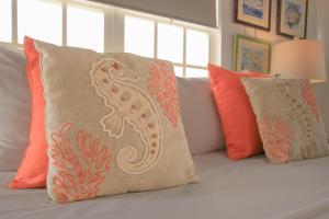 eine Couch mit orangefarbenen Kissen und einem Seepferdchenkissen in der Unterkunft Treasure By The Sea Bonaire in Kralendijk