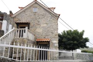 an old stone house with a white fence at Stone House in Salzedas