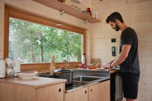 a man standing in a kitchen preparing food at Una Stanza con vista tra le colline senesi - Friland in Fattoria Falsini