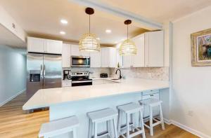 a kitchen with white cabinets and a counter with stools at Lighthouse Village #421 in Ocean City