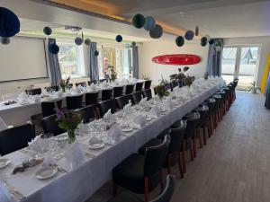 ein langer Tisch in einem Raum mit Tischen und Stühlen in der Unterkunft VØ Drop Inn in Nørre Vorupør