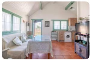 een woonkamer met een witte bank en een glazen tafel bij La Cabaña de Doñana in El Rocío