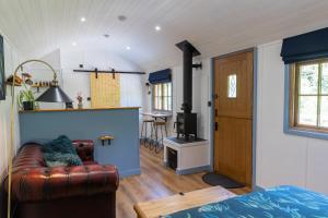 a living room with a couch and a kitchen at Kingfisher - Dog Friendly Luxury Glamping in North Devon in Buckland Brewer