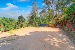 un camino de tierra con árboles en el fondo en Hotel O Kunchithanny Road Munnar, en Munnar