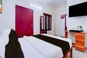 1 dormitorio con 1 cama grande y puerta roja en Hotel O Kunchithanny Road Munnar, en Munnar 17 fotos más