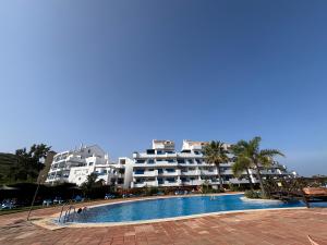 a hotel with a swimming pool in front of a building at Puerto de la Duquesa MINIMUM 3 NUITS in Manilva
