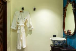 a robe hanging on a wall next to a sink at Sengphachanh Heritage Boutique in Luang Prabang +62 photos