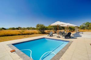 een zwembad met stoelen en een parasol bij Amani Lodge - Villa 81 in Warmbaths
