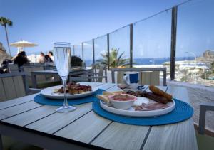 a table with two plates of food and a glass of wine at Holiday Club Puerto Calma in Puerto Rico de Gran Canaria