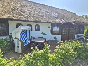 a house with a thatched roof with a table and chairs at Fischstübchen Neeberg Apt 1 – Wald und Wiese in Krummin