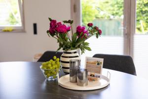 a table with a vase of flowers and a bowl of grapes at VITA Sonnholm - Ferienhaus mit Sauna, Ofen und Garten in Westerholz