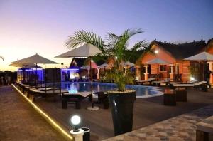 un complejo con piscina, mesas y sombrillas en Hôtel Blue Bay Madagascar, en Amborovy