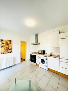 eine Küche mit weißen Schränken und einer Waschmaschine in der Unterkunft Stylish 2BR Shared Apt, Sleeps 6 Direct City Access in Wien + 30 Fotos