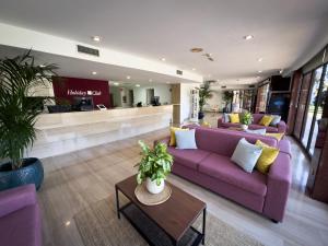 a living room with purple couches and a table at Holiday Club Puerto Calma in Puerto Rico de Gran Canaria