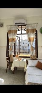 a room with two beds and a table and a window at Hotel Ngọc My in Phan Thiet