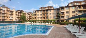 a swimming pool with white chairs and some buildings at Студио Sand, к-с Нестинарка in Tsarevo
