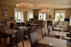 a restaurant with wooden tables and chairs and chandeliers at B&B Amylia in Wenduine