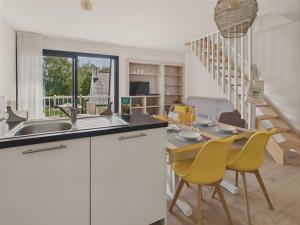 a kitchen with a sink and a table with yellow chairs at 300 m de la plage - Appart pour 4 avec balcon in Beg-Meil
